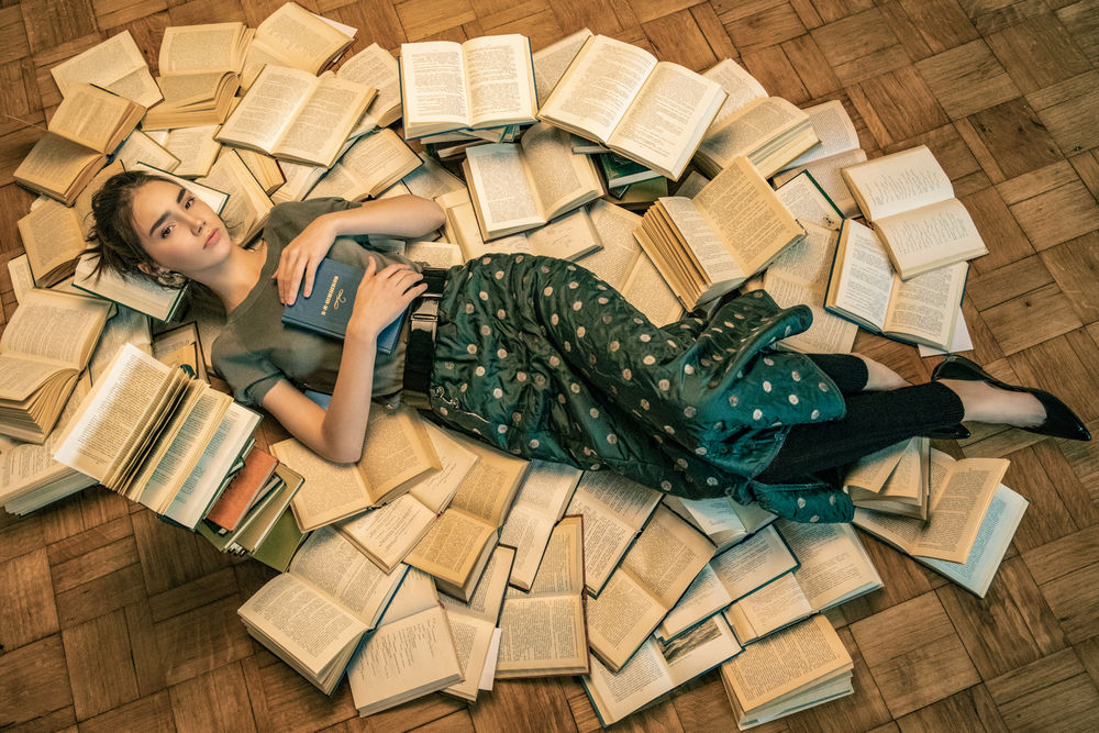 Обои для рабочего стола Модель Анна Пагута с книгой в руке лежит на полу в окружении книг, by Ilya Blinov
