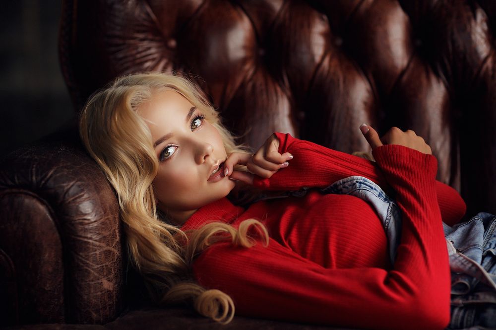 Обои для рабочего стола Модель Катерина Ширяева в красном свитере лежит на кожаном диване, foto by Dmitry Arhar