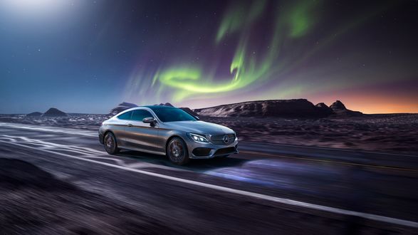 Обои на рабочий стол Серый Mercedes-Benz C-Class мчится по трассе на фоне северного сияния в ночном небе
