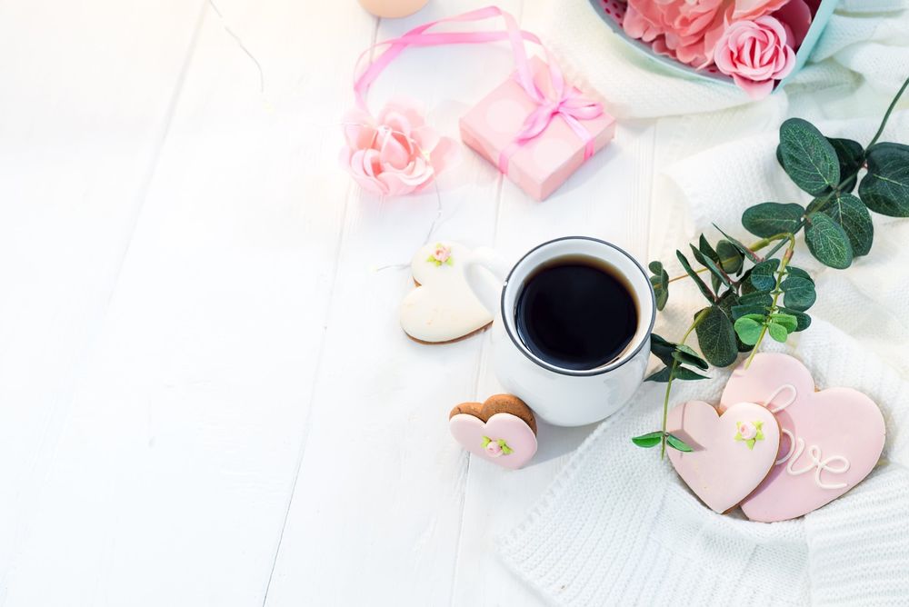 Обои для рабочего стола Коробочка с цветами, чашка кофе и печенья в форме сердечек с розовой глазурью, на одном из которых написано Love / Любовь