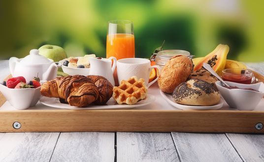 Обои на рабочий стол Вкусный завтрак: мюсли, круассаны, свежие ягоды, маракуйя, апельсиновый сок, вафля, булочки, джем в пиале, молочник и чашка кофе на подносе
