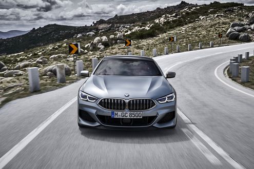 Обои на рабочий стол Серебристый BMW M850i xDrive GranCoupe едет по трассе на фоне гор