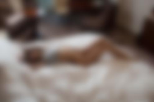 Обои на рабочий стол Полуобнаженная девушка в приподнятой футболке лежит на кровати в комнате