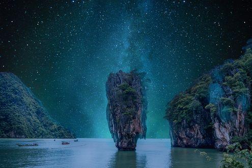 Обои на рабочий стол Лодки плывут среди скал в море звездной ночью, by enriquelopezgarre