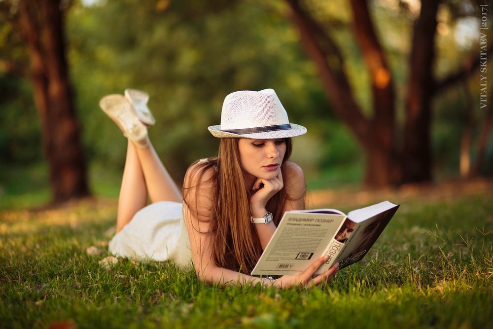 Обои для рабочего стола Девушка Виктория в шляпке с книгой в руке лежит на траве, фотограф Виталий Скитаев