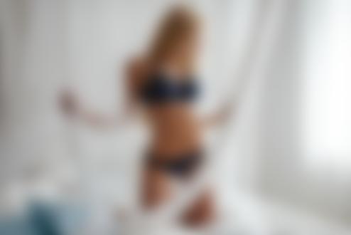 Обои для рабочего стола Длинноволосая блондинка Дана в темном нижнем белье стоит на коленях на кровати в спальной комнате