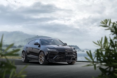 Обои на рабочий стол Черный Lamborghini Urus 2019 стоит на фоне гор и скал у моря