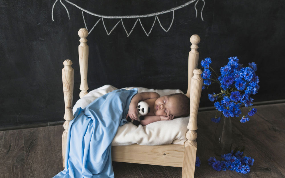 Обои для рабочего стола Маленький ребенок спит в деревянной кроватке с игрушечной пандой в руке