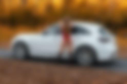 Обои для рабочего стола Девушка в красном нижнем белье и сапогах стоит у авто на дороге на фоне осенних деревьев