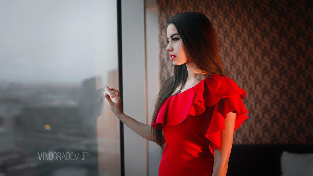 Обои для рабочего стола Модель Алина в красном платье стоит у окна, by Jeff Vinogradov