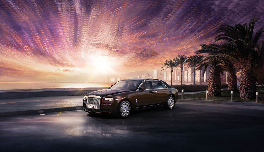 Обои для рабочего стола Коричневый Rolls-Royce Ghost стоит у пальм на морской набережной под вечерним небом