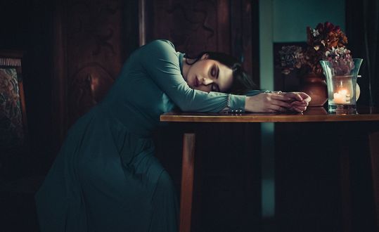 Обои на рабочий стол Модель сидит у стола, положив на него голову, фотограф Janusz Zolnierczyk