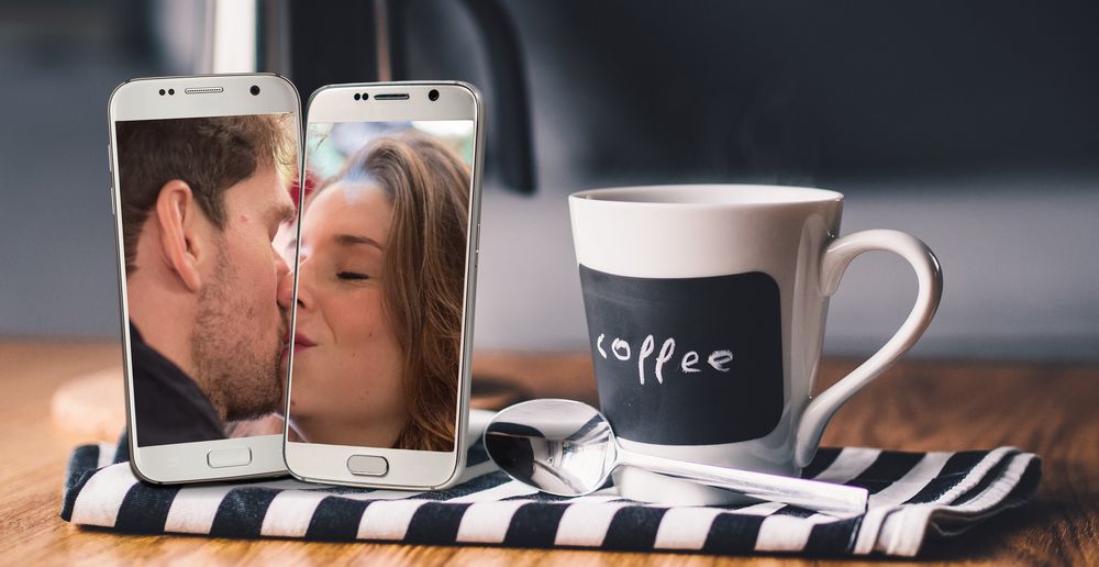 Обои для рабочего стола Два телефона с изображением на экране парня и девушки рядом с чашкой и ложкой, by Gerd Altmann