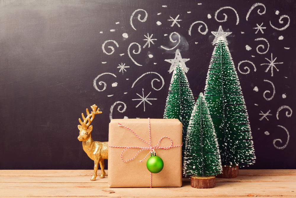 Обои для рабочего стола Три новогодние елки на фоне расписного фона и подарок с шариком и за ним игрушечный олень