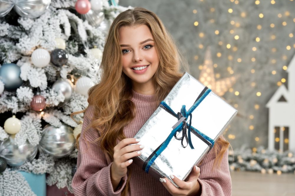 Обои для рабочего стола Модель Кристина Коснырева с подарком в руках на фоне новогодней елки