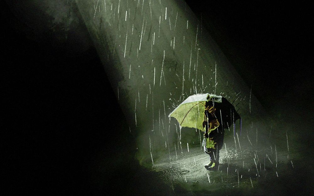 Обои для рабочего стола Девушка стоит под дождем с зонтом, освещенная прожекторами, иллюстратор Maxim Buyanov