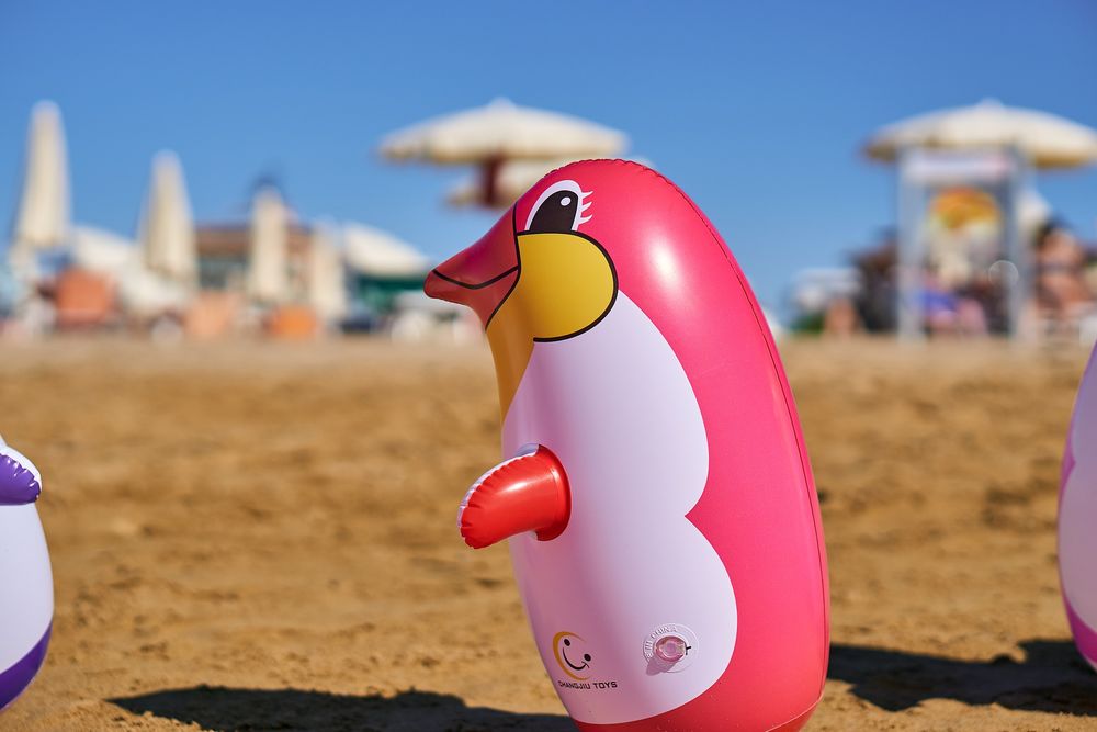 Обои для рабочего стола Надувная игрушка пингвина на песке пляжа, by Markus Distelrath