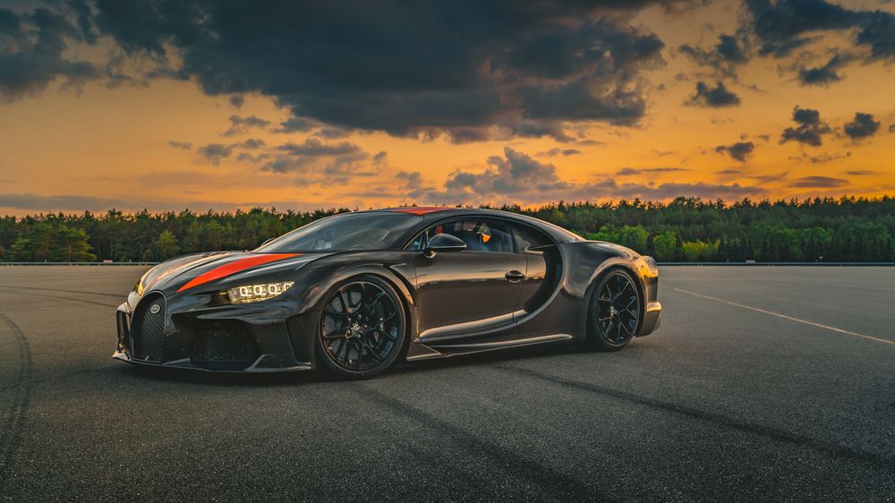 Обои для рабочего стола Черный с оранжевыми полосами Bugatti Chiron Super Sport 2019 стоит на треке под вечерним небом