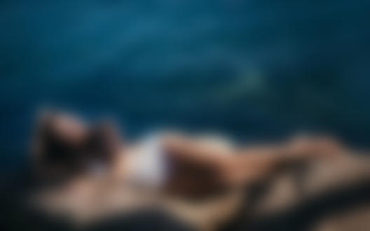 Обои на рабочий стол Модель Карина Попова лежит на камне у моря