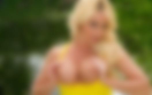 Обои для рабочего стола Порномодель Angela Sommers в желтой маечке держит руками обнаженную грудь на фоне зелени