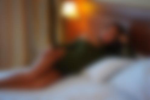 Обои для рабочего стола Модель с длинными волосами лежит на кровати