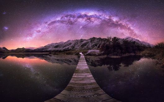 Обои на рабочий стол Подвесной мост через Mock Lake, Queenstown, New Zealand / озеро Мок, Квинстаун, Новая Зеландия к подножью гор на фоне млечного пути в ночном небе, by Jordan McInally