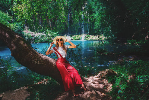 Обои на рабочий стол Девушка в шляпе сидит на дереве на фоне водопада. Фотограф Вилькевич Сергей
