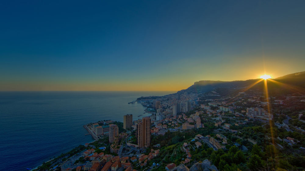 Обои для рабочего стола Город Монако в лучах восходящего солнца на фоне моря