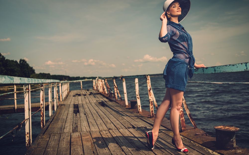Обои для рабочего стола Девушка в шляпе стоит на мостике на фоне моря, автор nejron