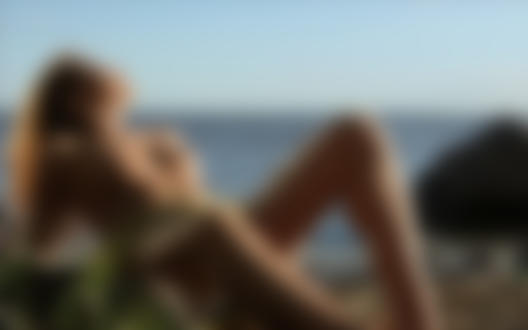 Обои на рабочий стол Девушка лежит на каменистом берегу на фоне моря