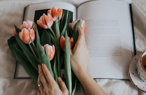 Обои на рабочий стол В руках девушки тюльпаны на открытой книге