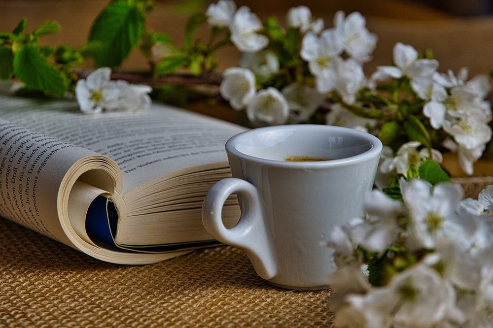 Обои для рабочего стола Чашка кофе стоит рядом с книгой и весенними цветущими веточками вишни, by Anrita