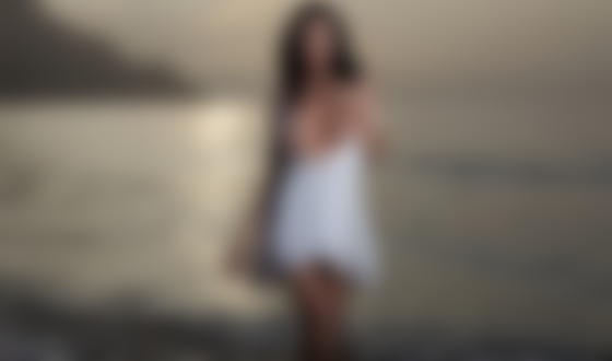 Обои для рабочего стола Модель Anastasya M с обнаженной грудью стоит вечером на берегу моря