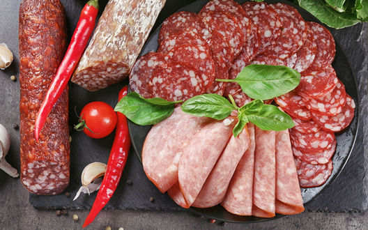 Обои на рабочий стол Тарелка с мясной нарезкой, листьями салата, чесноком, помидором-черри и красным перцем