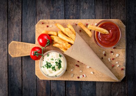 Обои на рабочий стол Доска с пакетом фри, томатами и соусами