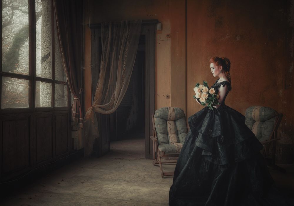 Обои для рабочего стола Девушка в длинном пышном платье стоит в комнате с букетом роз, фотограф Sergii Vidov