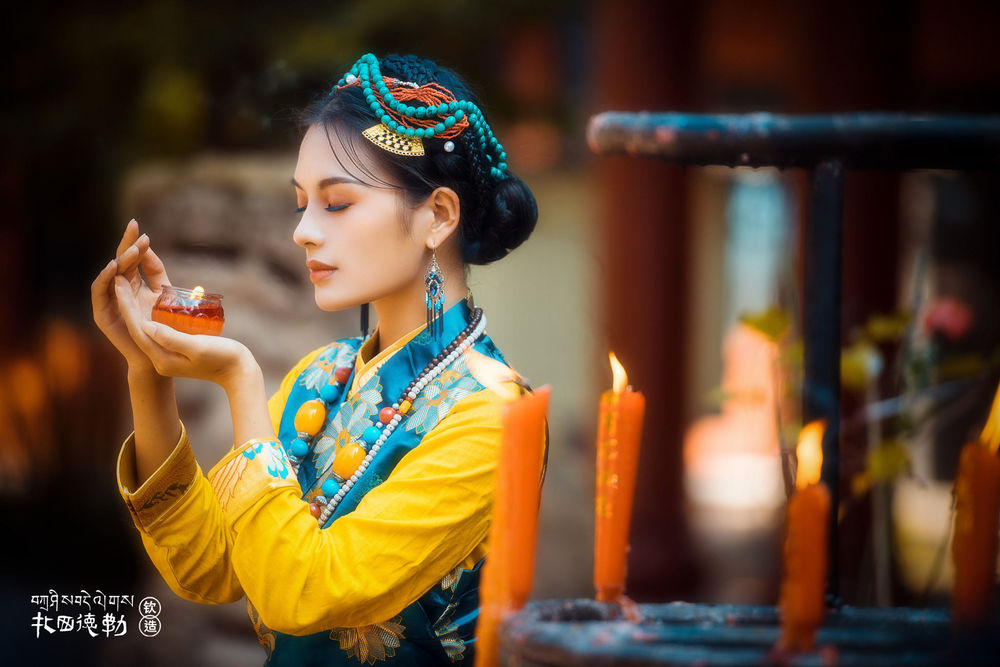 Обои для рабочего стола Девушка азиатской внешности держит в руке баночку и стоит у горящих свечей