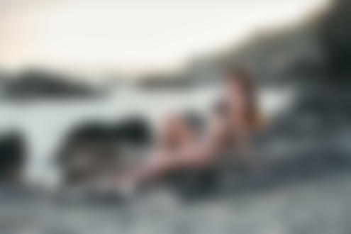 Обои на рабочий стол Девушка в купальнике сидит на камне у воды