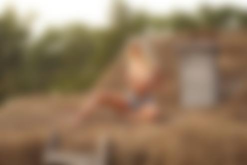 Обои для рабочего стола Блондинка Мария Автахова в расстегнутых джинсовых шортах топлес сидит на соломе на крыше дома, фотограф Андрей Попов