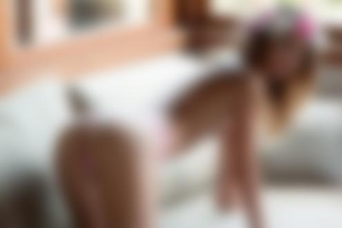 Обои для рабочего стола Модель Monique Helena в розовых трусиках и с венком на голове топлес стоит на четвереньках на диване в комнате