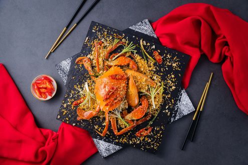 Обои на рабочий стол Китайская кухня: краб со специями на квадратном блюде, рядом палочки для еды и красная ткань, вид сверху