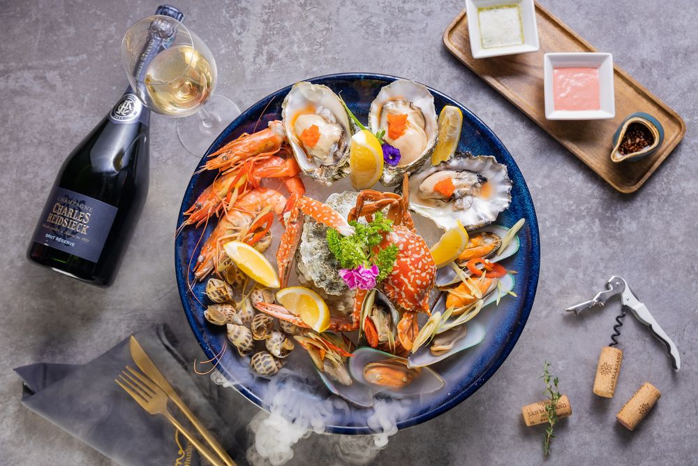 Обои для рабочего стола Азиатская кухня, блюдо из морепродуктов- креветки, мидии, кальмар с бульоном, рядом соусы и шампанское, вид сверху