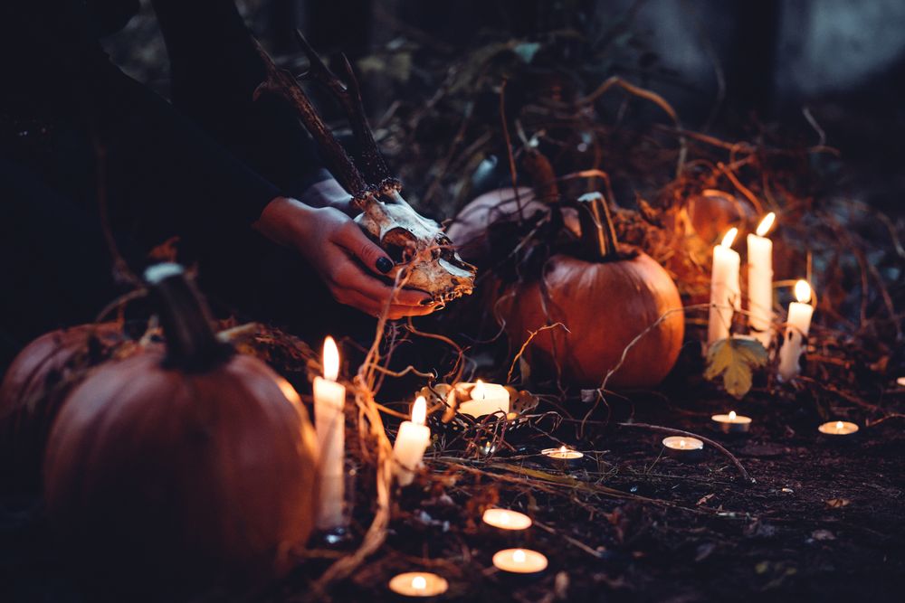 Обои для рабочего стола Ведьма с черепом в руках в окружении горящих свечей и тыкв совершает ритуал в ночь Хэллоуина, by freestocks