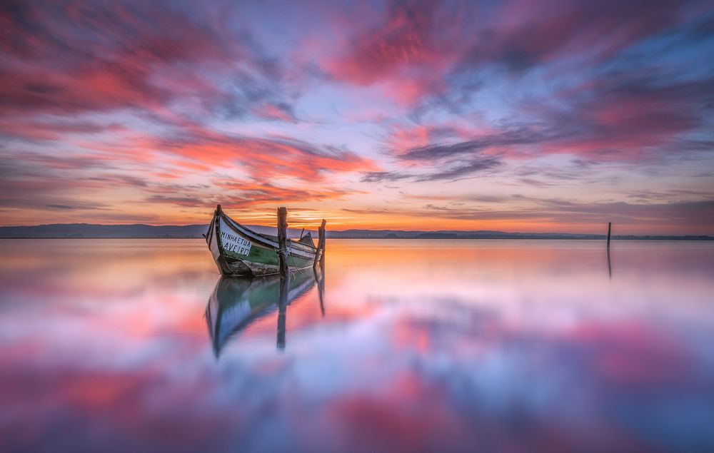 Обои для рабочего стола Лодка стоящая в озере на фоне заката солнца