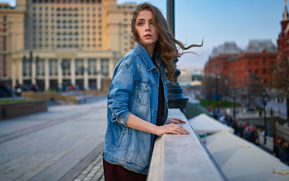 Обои для рабочего стола Модель Ксения в джинсовой куртке стоит на улице города, фотограф Sergey Fat
