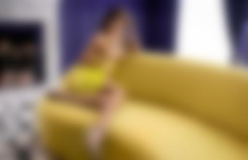 Обои для рабочего стола Модель Кристина Макарова в приспущенном платье топлес сидит на диване в комнате, фотограф Владимир Николаев