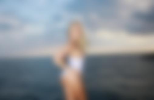 Обои на рабочий стол Украинская эротическая фотомодель Liza B / Елизавета Воронина стоит в белой майке на фоне моря