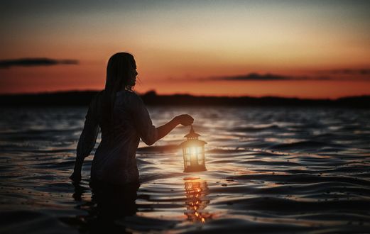 Обои на рабочий стол Девушка с фонарем в руке стоит в воде, фотограф Mikkel Gaba