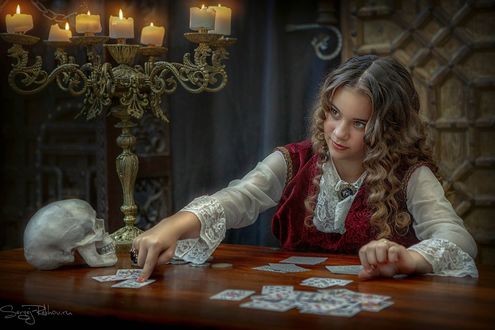 Обои на рабочий стол Девушка -гадалка сидит перед картами за столом. Фотограф Рехов Сергей