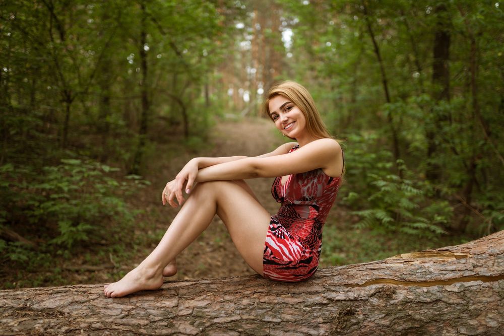 Обои для рабочего стола Светловолосая девушка в пестром платье сидит на бревне в лесу, фотограф Андрей Филоненко